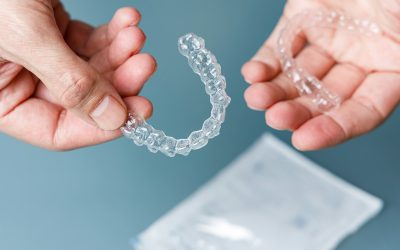 Hands holding transparent aligners. Invisalign orthodontics concept